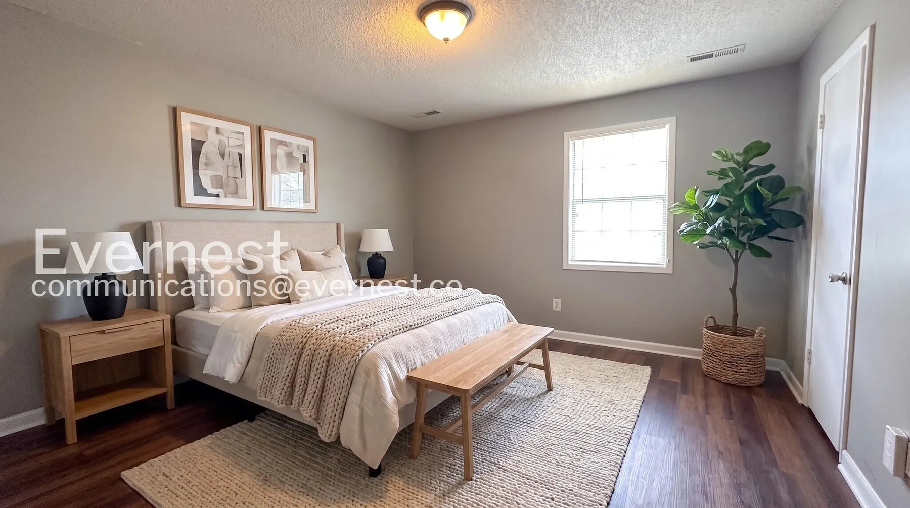 Virtually staged Midtown Manor bedroom with a neutral upholstered bed and wood-look flooring