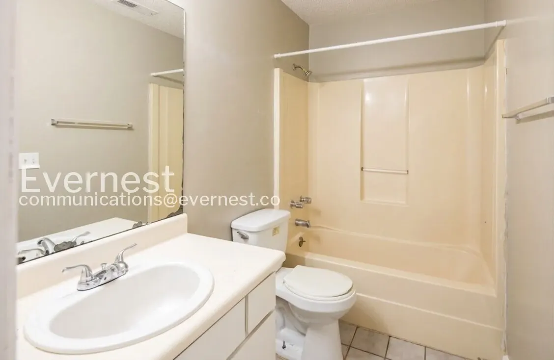 Midtown Manor bathroom with a vanity, mirror, toilet, and tub-shower combination