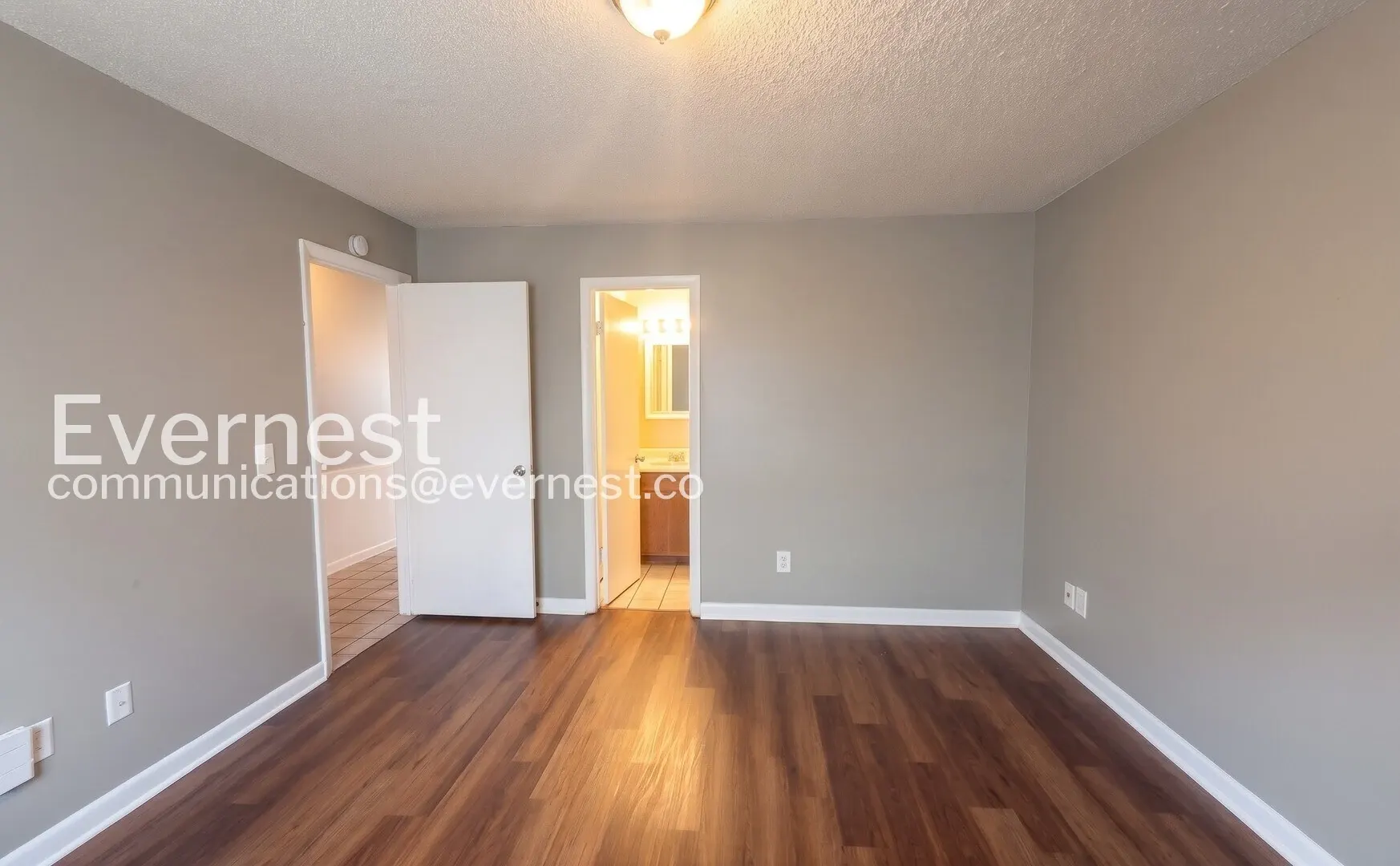 Unfurnished Midtown Manor bedroom with wood-look flooring and an adjoining bathroom doorway